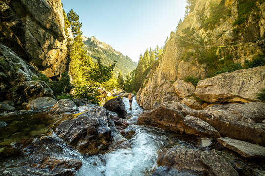 Adventurer standing in stream among mountains