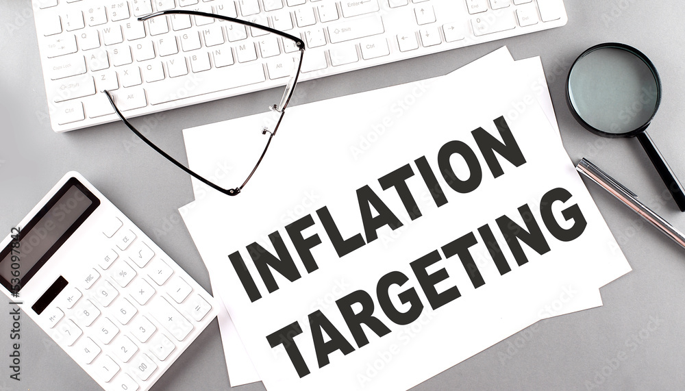 Aufkleber inflation targeting text on paper with keyboard, calculator on grey background