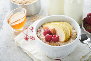 Oatmeal. Bowl of oatmeal porridge with raspberry, pear and honey on gray concrete old table background. Hot and healthy food for Breakfast, top view, flat lay