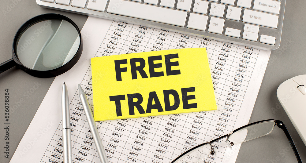 Poster free trade text written on a sticky on chart with keyboard and magnifier