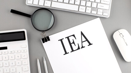 IEA written on paper with office tools and keyboard on the grey background