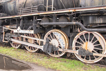 Fototapeta na wymiar Drive transmission mechanism in a historic and damaged steam locomotive standing on a sidetrack. Rail.