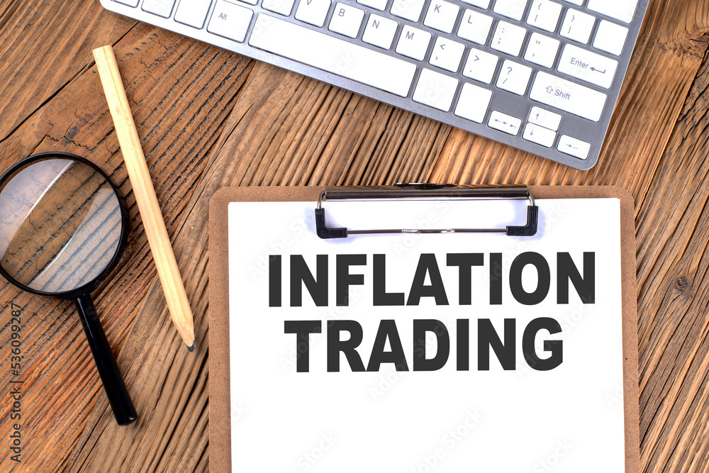 Aufkleber inflation targeting text on paper clipboard with magnifier and keyboard on wooden background