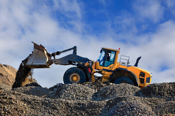 Yellow Wheel Loader Working at Construction Site, Blue Sky Clouds Background. 