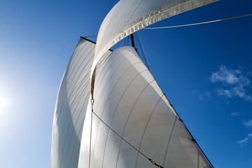 white sails of a boat on a blue sky