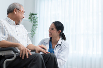 Asian female doctor telling funny story to senior man sitting on wheelchair. Grandfather laughing and happy at nursing home. Tae care and support aged people.
