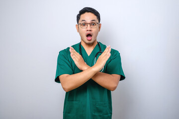 Shocked-looking male nurse, doctor in green scrubs cross hands in stop sign, prohibit or forbid...