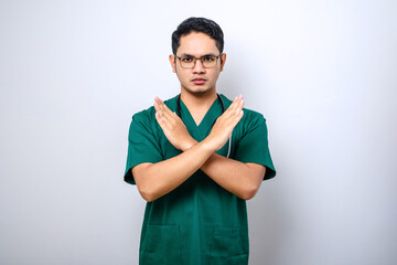 Angry serious-looking male nurse, doctor in green scrubs cross hands in stop sign, prohibit or...