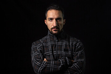 Portrait of a serious man with folded hands on a black background. Stylish male portrait