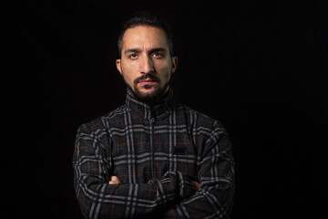 Portrait of a serious man with folded hands on a black background. Stylish male portrait