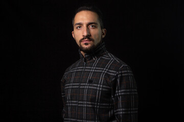 Portrait of a guy in a tracksuit on a black background. Stylish male portrait