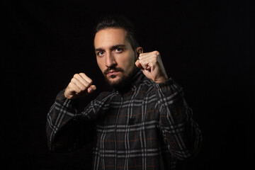 Portrait of a man in a combat stance on a black background. Stylish male portrait