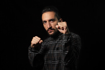 Portrait of a man in a combat stance on a black background. Stylish male portrait