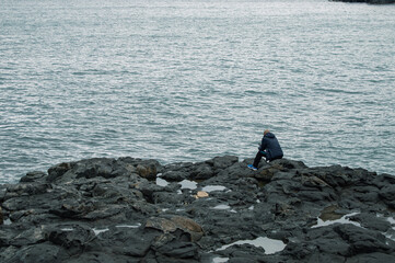 Triste hombre sentado solo en las piedras de la isla