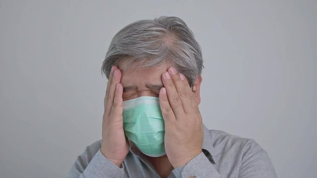 Sick Asian man wearing a medical face mask and Take a hand to hold the headache in the head. Concept of protection pandemic coronavirus and respiratory disease