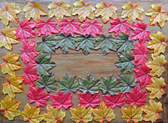 Multicolored autumn artificial leaves lie on a wooden background for copyspace
