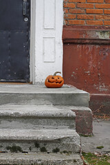 Scary pumpkin as halloween decoration stands at the front door on the street