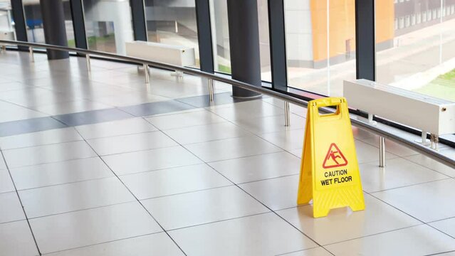 Cleaning service indoors. Yellow plastic caution sign - beware slippery on the floor at airport or shopping mall hall. Nobody