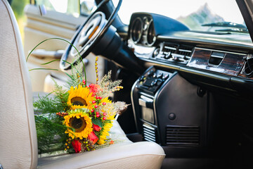 Sunflower wedding bouquet on the passenger seat of an old classic car of the bride