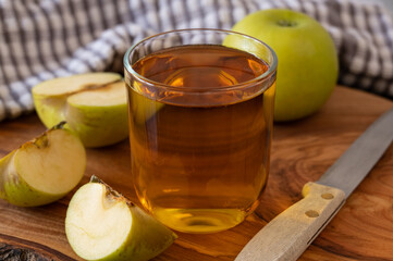 Glass of Apple juice on wooden cutting board with chopped and full apple