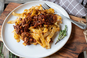 Italian ragout with chicken, tomatoes, onions, garlic, herbs and red wine sauce on a plate with tagliatelle