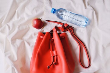 Women's red handbag, apple and water bottle. Flat lay fashion photography, top view