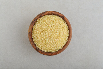 Raw couscous  in wooden bowl  on concrete background. Top view