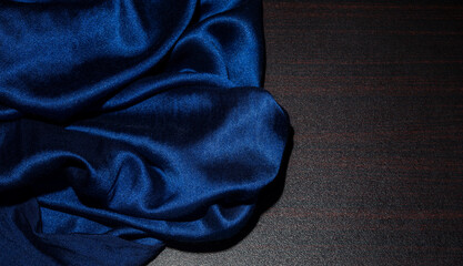 Luxury blue silk fabric on dark brown wood table with copy space