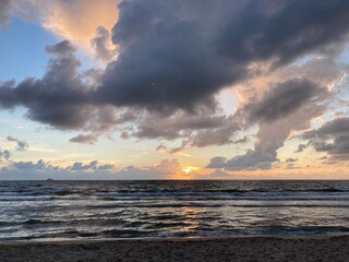 at the sea the red-golden sun shines out from behind the clouds before it sets