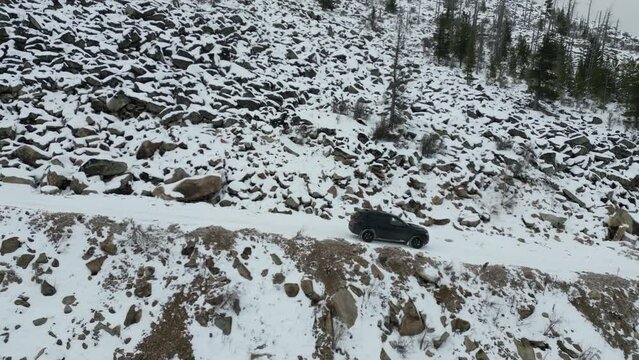 Flying a drone behind a car in the winter mountains. jeep grand cherokee wk2 in the snow in the forest . side view