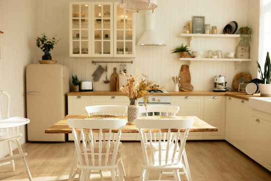 Picture of white cozy kitchen of scandinavian style with counter, oven, furniture and refrigerator, table and chairs in the middle of room. Design project, renting flat advertisement