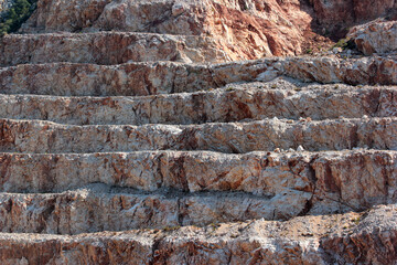 Side view of construction aggregate quarry, stepped slope of a mountain
