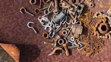 Rusted screws, nuts and bolts in a rusty iron case,
rusty nails, rusty chains, These rusty metal parts appear on the surface, rust background.