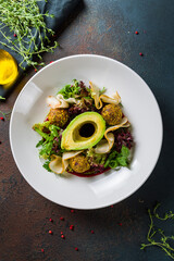 vegetable salad with avocado,pear and falafel on white plate top view, vertical
