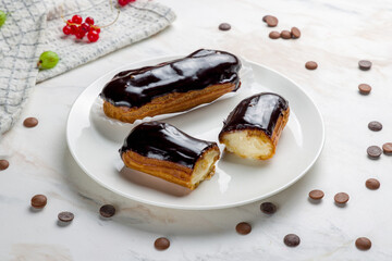 chocolate Eclair on a white plate on marble table