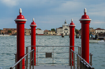 Quattro paline rosse, i tipici pali da ormeggio veneziani, affacciati sul bacino di San Marco in...