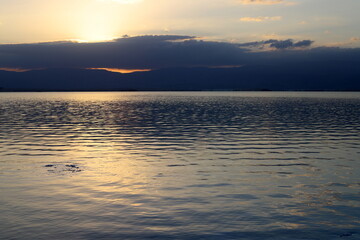 Sunrise on the shore of the Dead Sea in Israel. The sun rises from behind the mountains in Jordan.