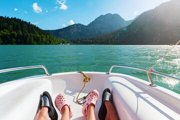 Boat travel trip on sunny summer vacation day. Legs of mom and baby.Water and mountain nature...