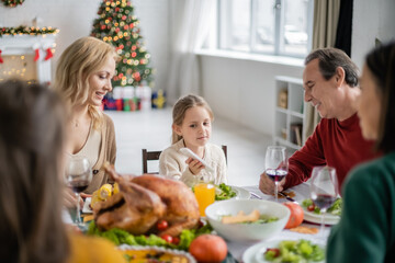 Kid holding smartphone near smiling grandparent during thanksgiving dinner at home