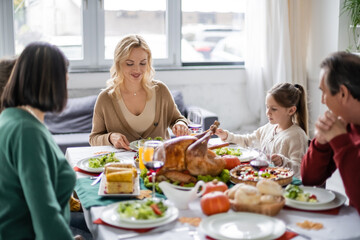 Positive woman sitting near parents and children during thanksgiving dinner at home