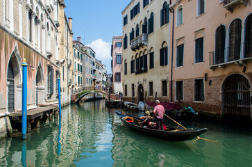 Een gondel navigeert op een zonnige dag door een kanaal in Venetië onder leiding van de gondelier in traditionele kleding