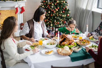 multiracial woman looking at granddaughter during christmas dinner with family