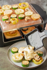 Delicious traditional Swiss melted raclette cheese on diced boiled or baked vegetables served in individual skillets.