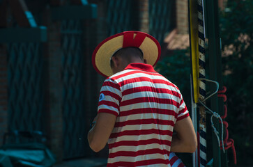 Un gondoliere nella tipica maglietta a righe e con il cappello di paglia attende i clienti per un giro in gondola a Venezia