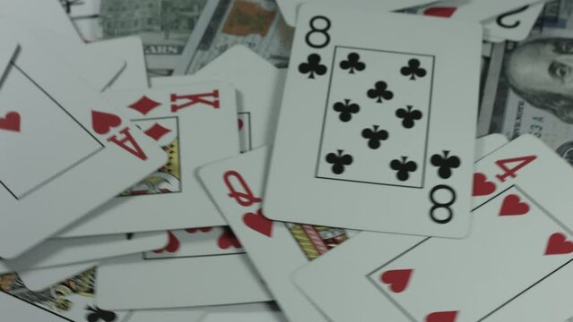 $100 Bills Cascade Onto Playing Cards Rotating White Background 4K