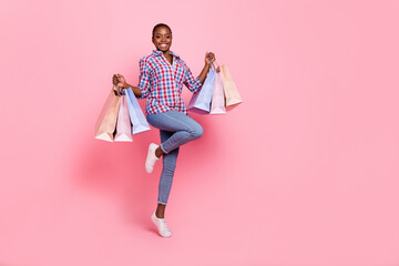 Full body portrait of carefree crazy lady hold boutique packages jump isolated on pink color background