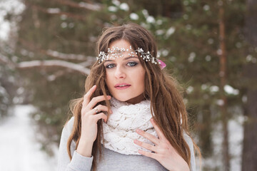 Beautiful bride in a white dress with a bouquet in a snow-covered winter forest. Portrait of the...