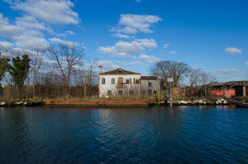 Fototapeta na wymiar Una casa dell'isola di Mazzorbetto vista dal canale in una giornata di sole e nuvole