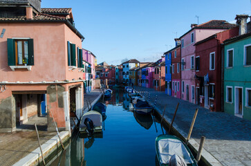 Barche ormeggiate in un canale di Burano con le tipiche case colorate in una giornata di sole 