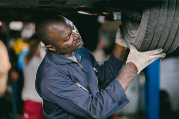 mechanic staff worker male checking car tire replace old tyre in auto garage service